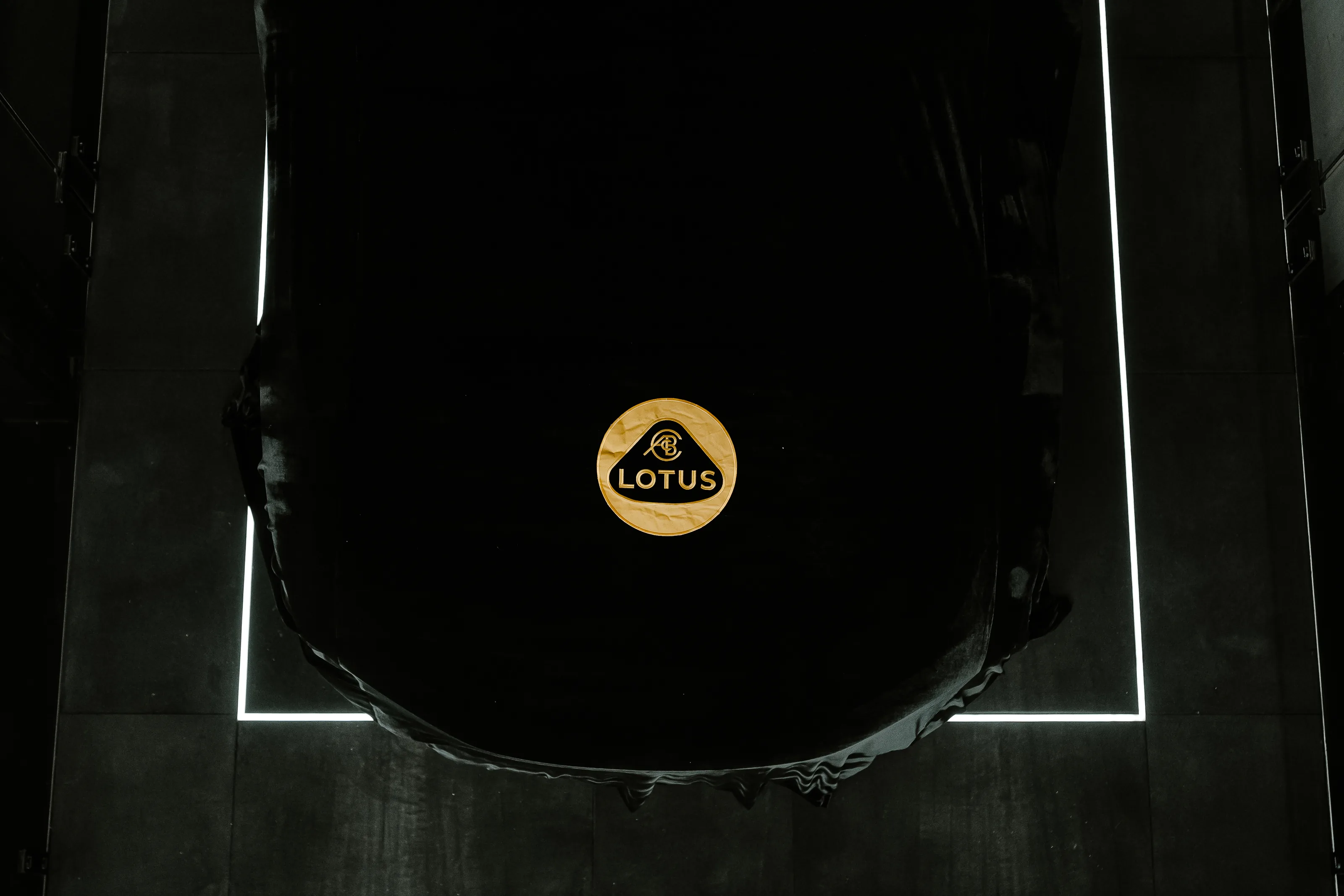 Carro coberto pela capa preta com o emblema dourado